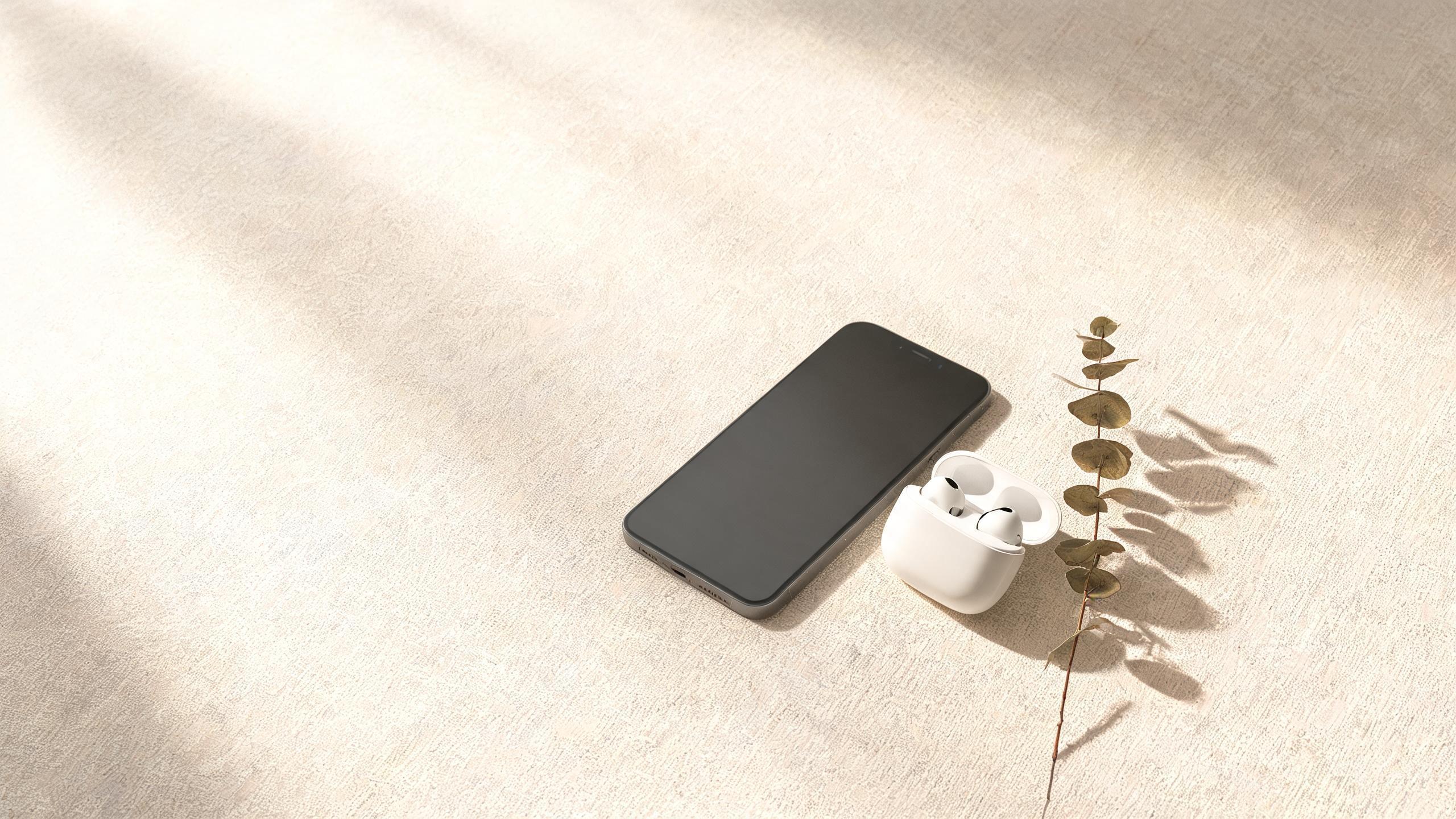 Smartphone and wireless earphones photographed on a warm linen surface
